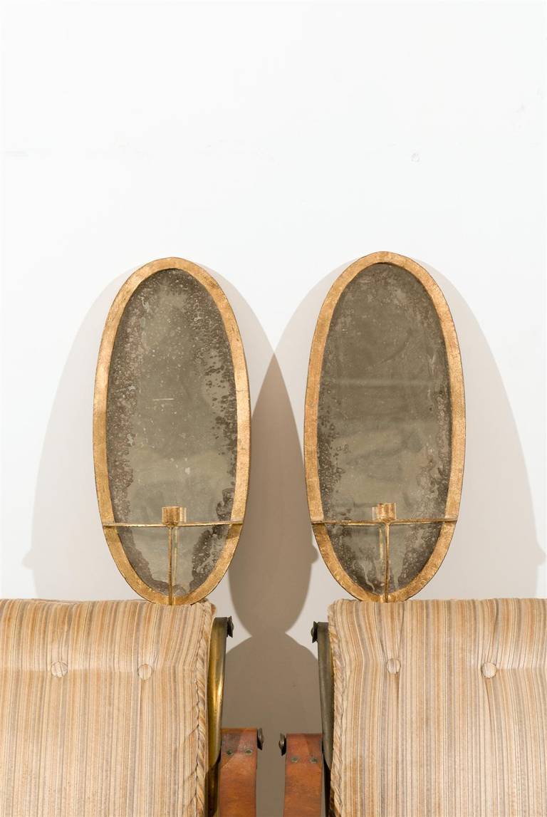 Pair of Oval Guilt Iron Sconces with Mirrored Backs.