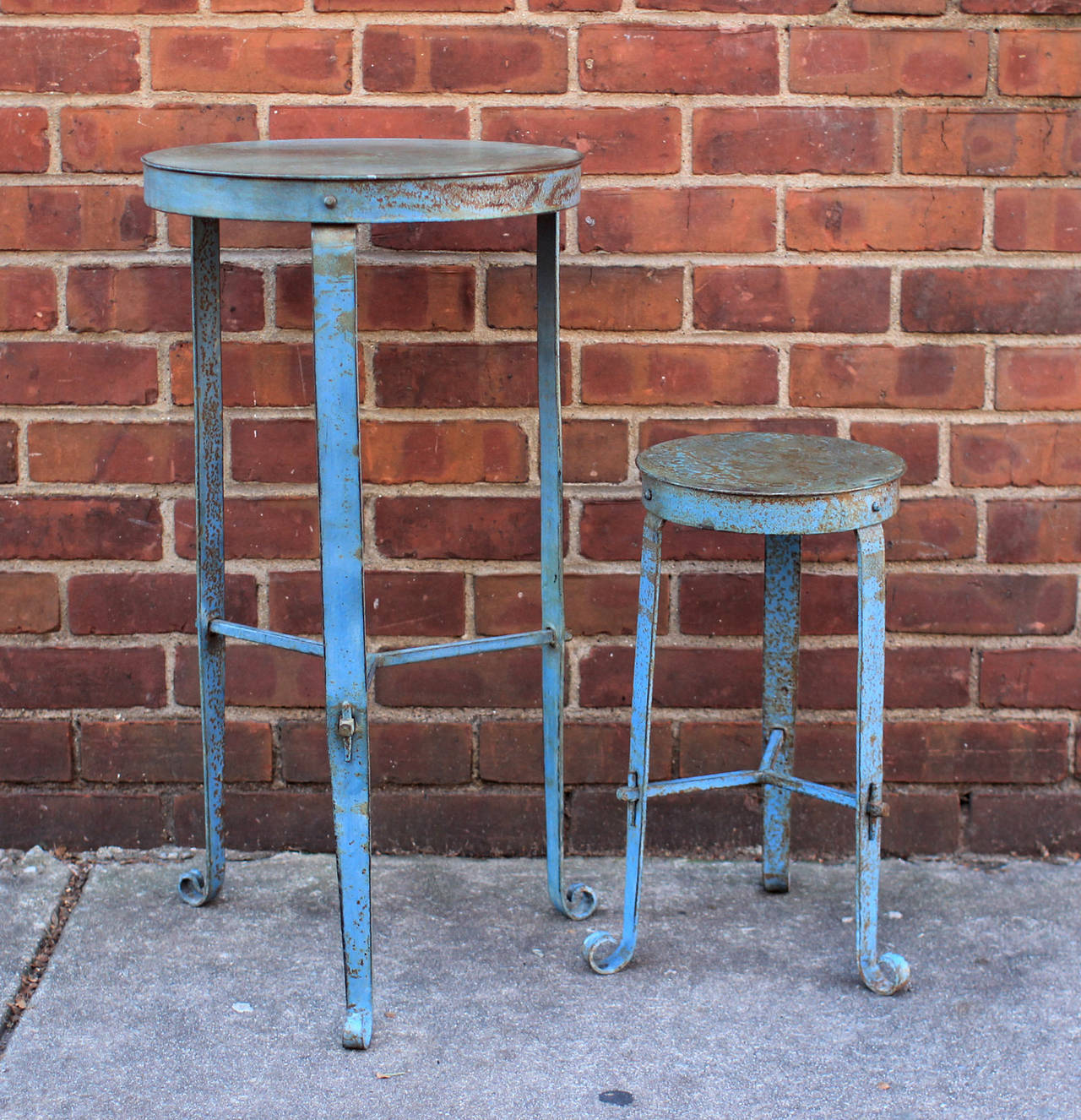 Pair of blue painted iron stands with Arts & Crafts details of faux peg construction and a whimsical curved foot; probably American, early 20th century. The smaller one measures 20