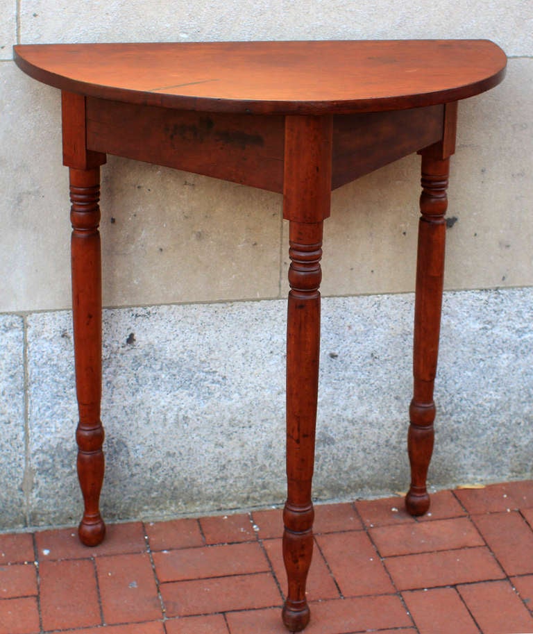 Handsome demi-lune table with turned legs, exaggerated height, good color and original finish. American, circa 1850. Nice overhang to the back. Excellent proportions. Very sturdy.