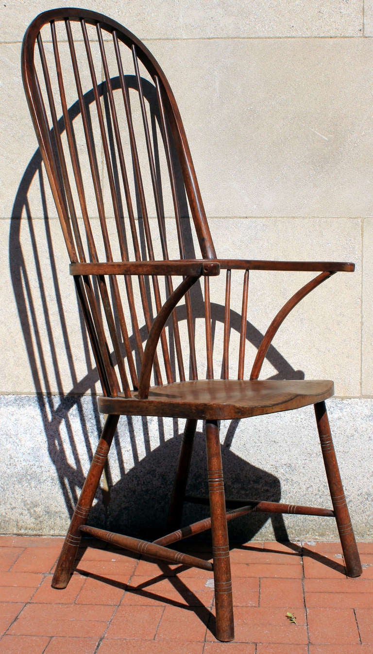 Handsome and sculptural Windsor arm chair with an exaggerated high back, turned legs and stretchers; English, circa 1870. Carved saddle seat and arm returns. Comfortable and sturdy. Very good color and patina.