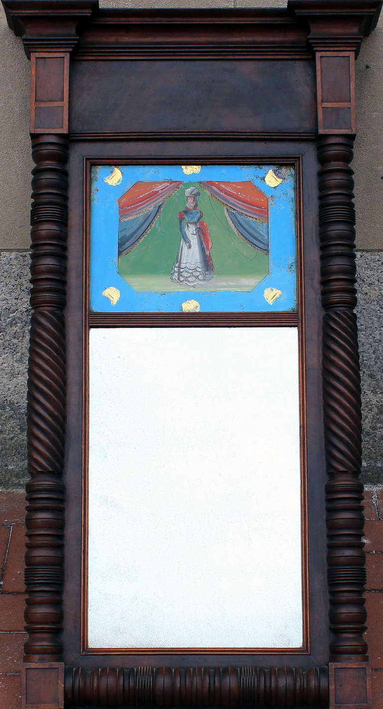 Federal mirror in mahogany frame with excellent cornice molding and outstanding turned pilasters. Fine eglomise (reverse paint on glass) painting of a woman on a stage in vibrant colors. All original including backboard, mirror and paint on glass;