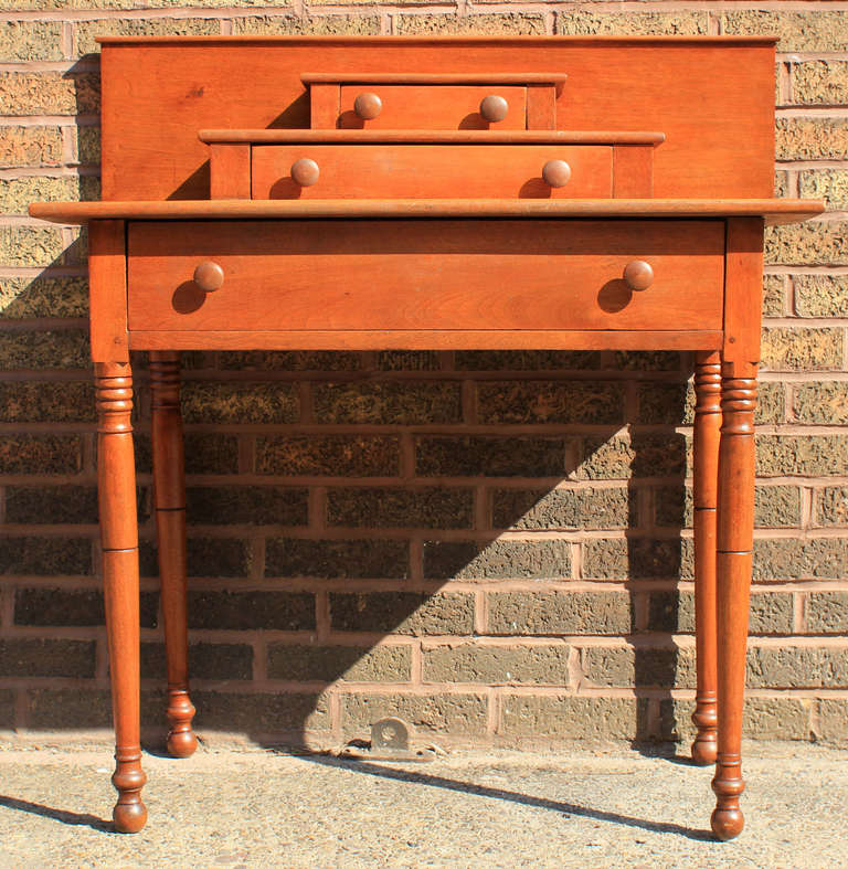 Handsome honey-colored walnut side table, with a strong square backsplash. 3 drawers in ascending size, turned knobs and legs, dovetailed drawers. Would make an excellent server or dressing table. New England, circa 1830. All original.