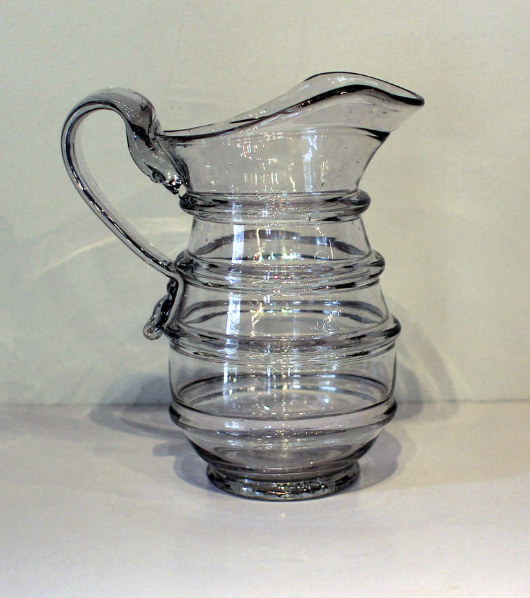 Fine and heavy hand-blown glass pitcher with applied handle and four-ring decoration, nice wide swooping spout and clean pontil. Probably Pittsburgh, circa 1850. Excellent clarity.