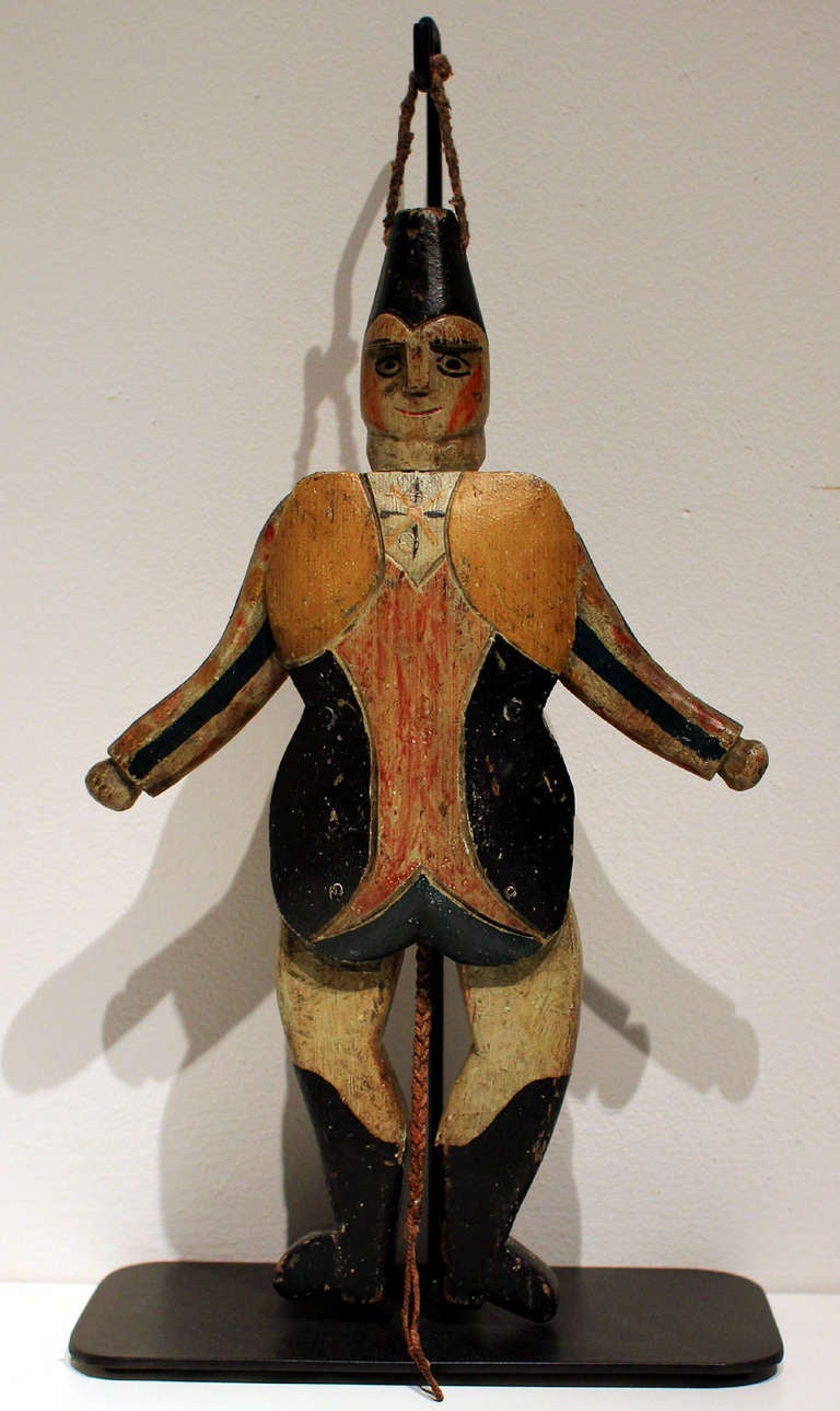 Articulated jumping jack harlequin, different figure on each side, original paint, original pull-string, but with one replaced toe; probably American, mid to late 19th century. Custom-made metal stand. Alone, the figure measures 12.5
