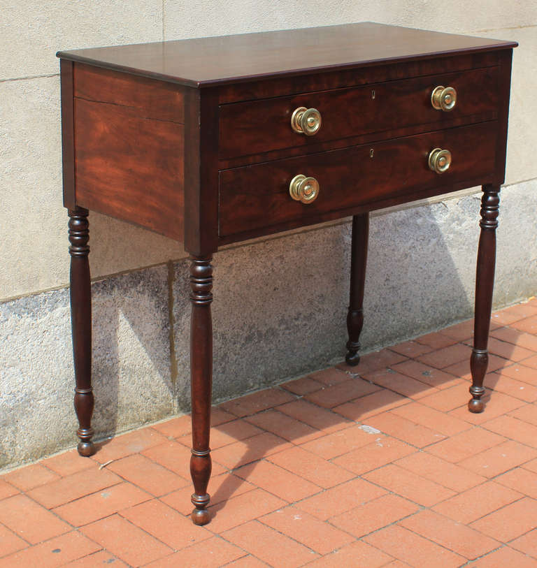 Fine mahogany server with nice proportions and excellent figure to the wood. Two drawers, pressed brass period knobs, turned legs, dovetail construction; American, circa 1830.