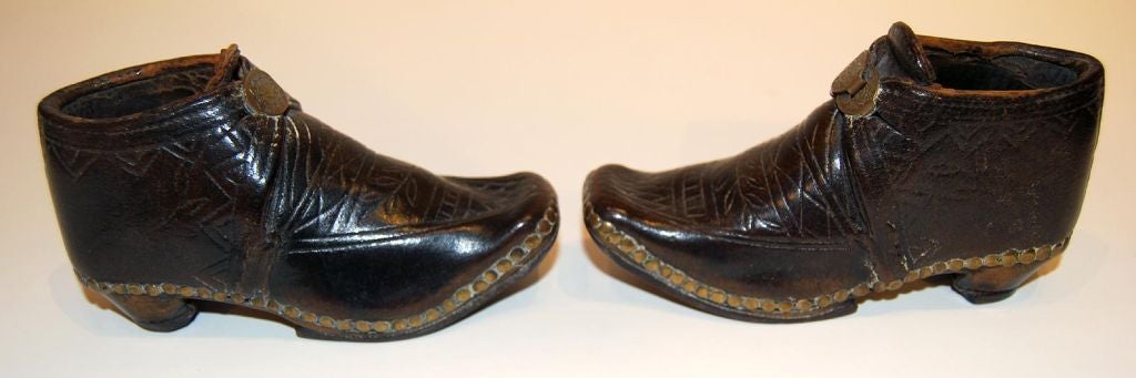 Charming little pair of leather shoes with brass studs and buckles, and iron horseshoes. A fine etched pattern is throughout the leather, and a pressed pattern in the buckles as well; early 19th century British Isles.