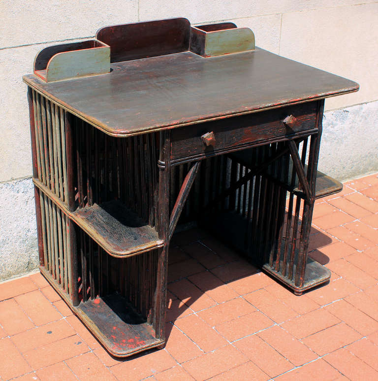 Unusual desk with a style spanning aesthetic to art deco, with an outstanding paint history that includes red, black and gold layers with craqulure. The desk has a terrific linear body formed of twigs, splints, dowels and shelves. The knobs on the