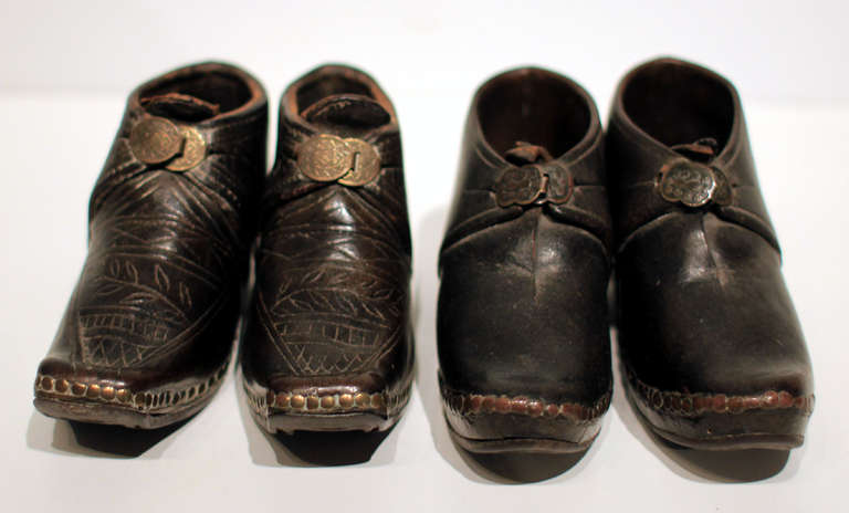 Rare and fine little pairs of leather shoes with brass studs and buckles, and iron horseshoes. One pair has a fine etched pattern is throughout the leather, and both have a nice pressed pattern in the buckles as well. Soles show wear, unusual for