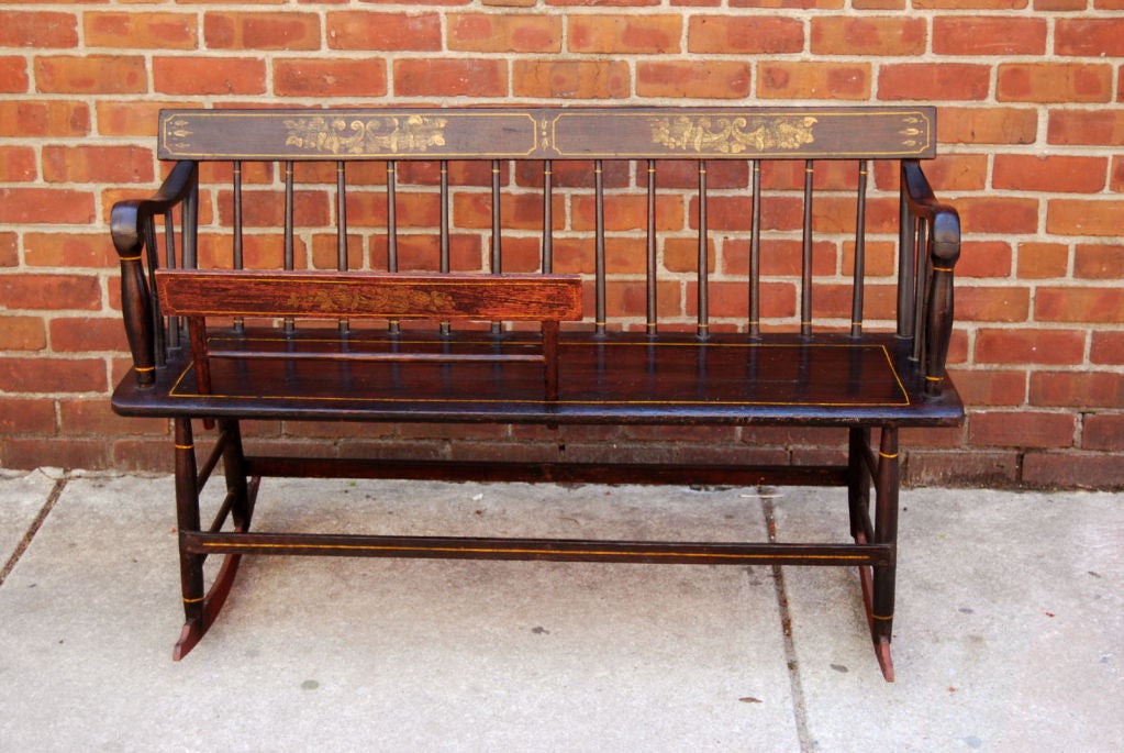 A very fine settee, historically known as a mammy bench on which a mother or nanny could sit next to a cradled child. The cradle arm is removable. Fine turned spindles and paint decorate the back of the bench, and along the arms where an additional
