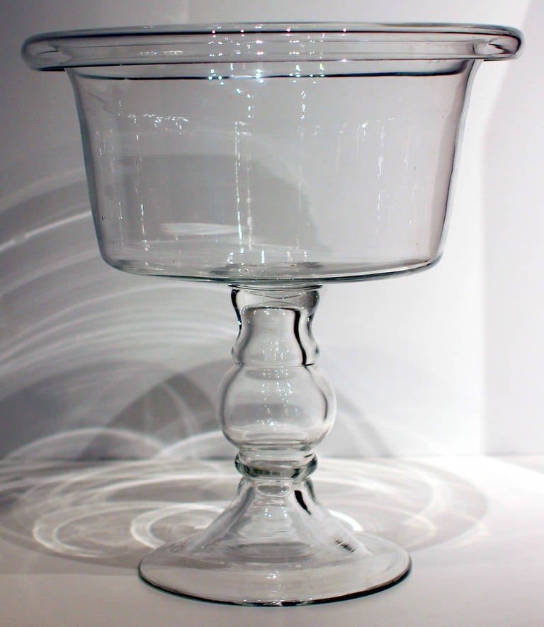 Dramatic and very large blown glass compote with exaggerated rolled lip, flat bottom and fine blown base. American, mid-19th century. Highly unusual form and size.