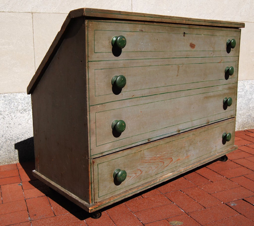 This unusual blanket chest was smartly designed and constructed to originally fit under the roof line of the top floor of a house. It rolls out on casters and the hinged lid opens back to reveal a chest space, while the facade gives the impression