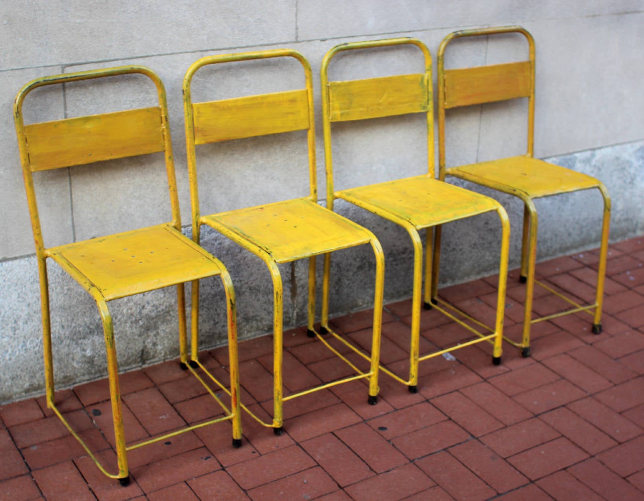 Set of four good-looking metal chairs in bright yellow paint, and some history of different colors of paint peaking through; American, circa 1940. Sturdy and comfortable. Priced as a set.