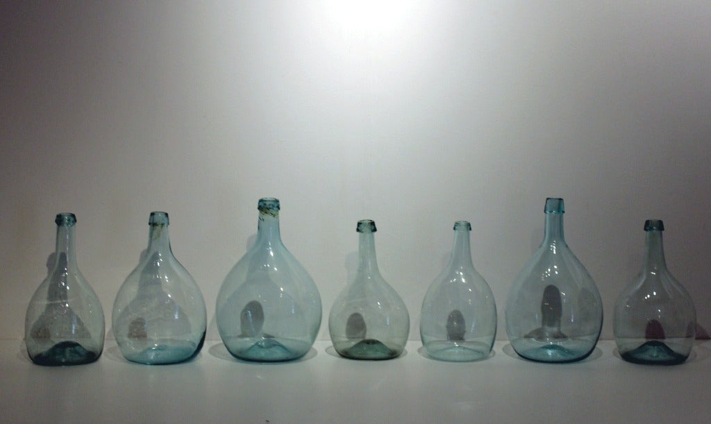 Terrific group of 7 very good blown glass bottles, ovoid shapes, aquamarine color, American, circa 1850. Great shapes and clarity to the glass.