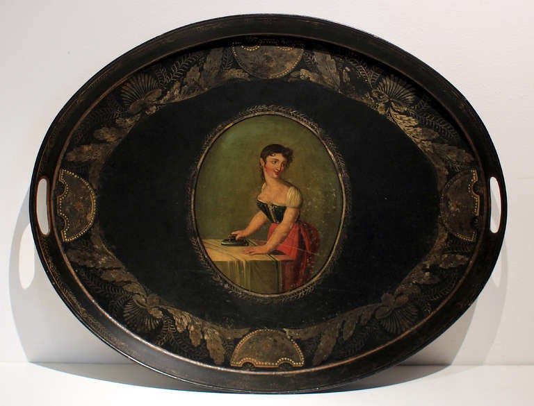 Handsome tole painted tray featuring an excellent painting of a woman ironing, an unusual, domestic portrayal. Two handles; English, mid 19th century. Nicely heavy.
