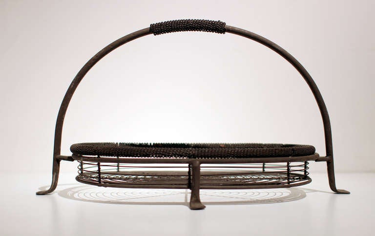 Shallow two-part wire basket / centerpiece with arching handled carrier, curly decorative handle and rim of basket, stamped feet; iron, late 19th century. Very strong and well made.