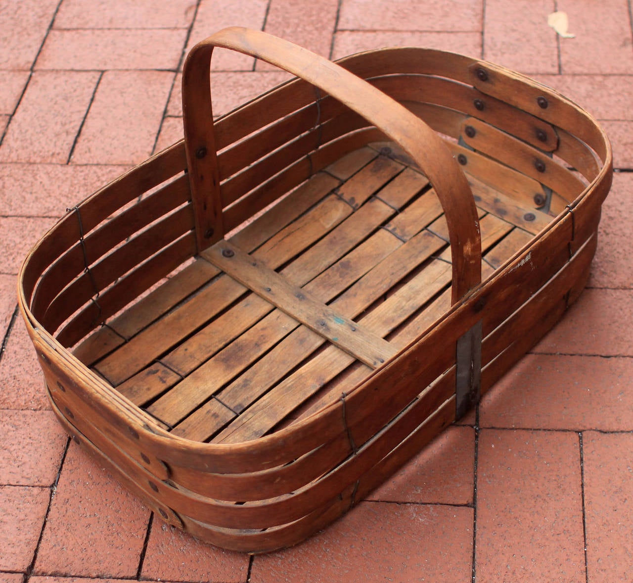 Handsome, oversized flat-bottom basket of slatted wood, metal and wire construction; American, late 19th century. Excellent patina.