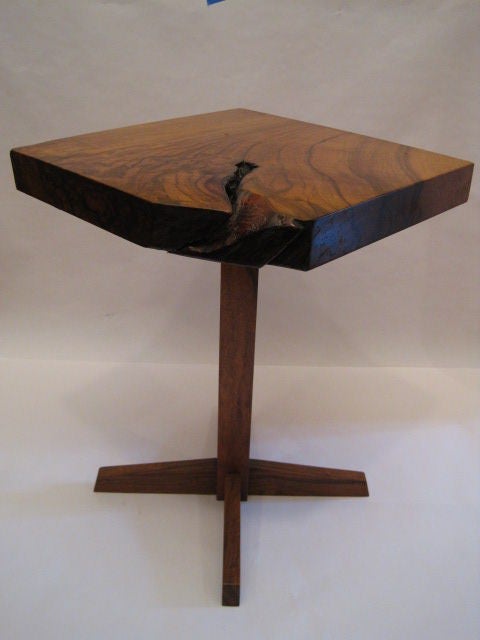 A rare squuare end table of English Walnut supported by a slender pedestal base and legs. The top has a wonderful marble grain thick is a full two inches thick giving it a more sturdy stance.This is a very rare form annd a great example of Nakashima.