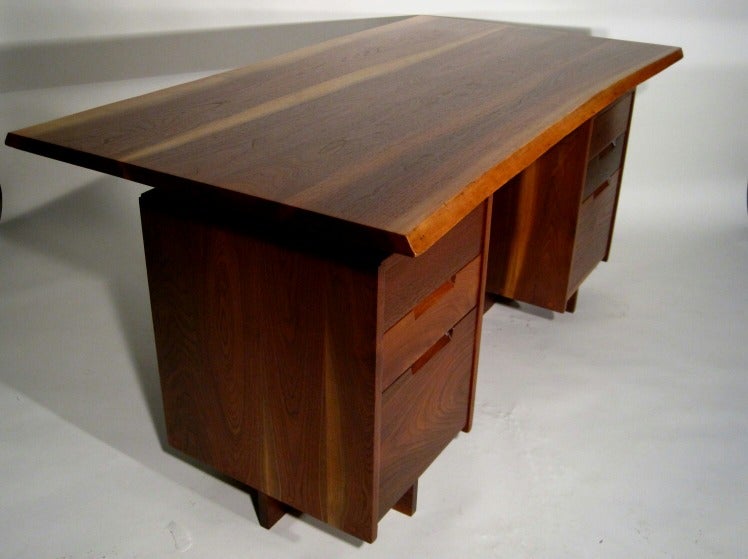 An Excellent example of a rare form by George Nakashima. Thick Walnut top with sapping through out each board makes this desk have the look of a musical instrument. The top also is thicker than most other examples that I have seen to date. A subtle