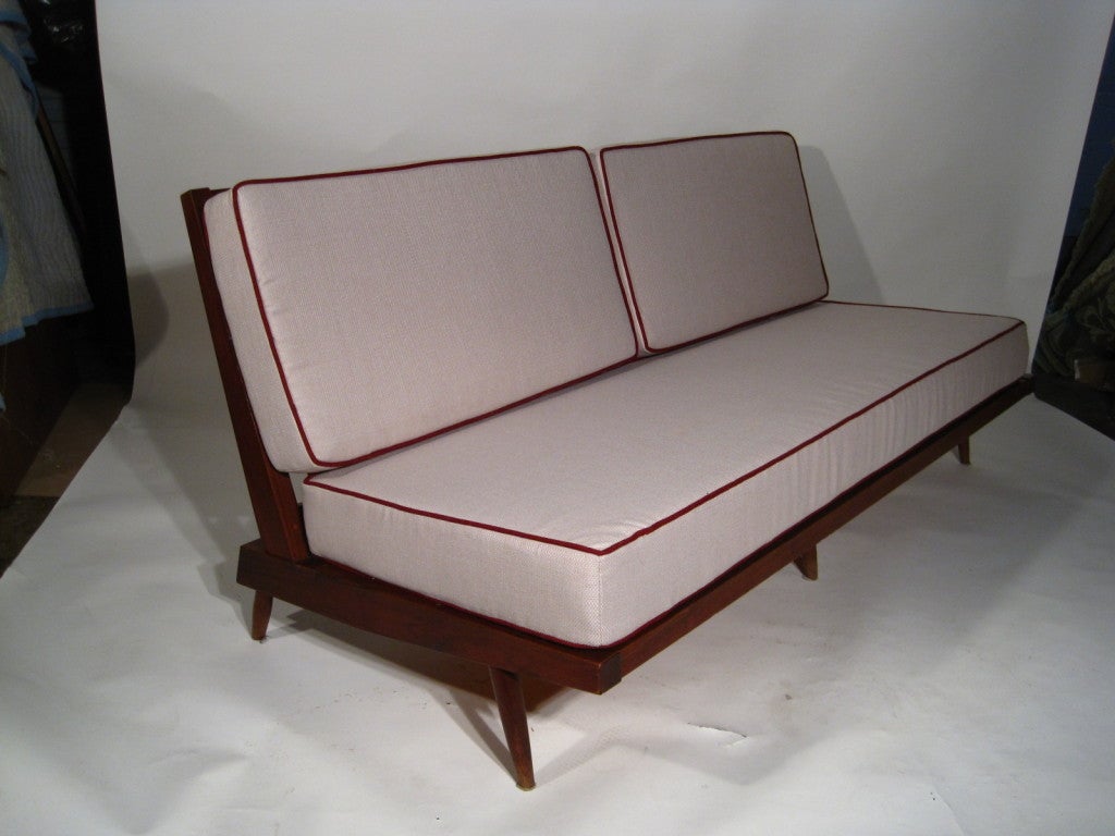 A Walnut sofa having a canted angled back for recline position. Very comfortable form. You are not forced to sit up in this piece. Foam seat and back cushions give firm support as well. This was one of Nakashima's most successful design forms.