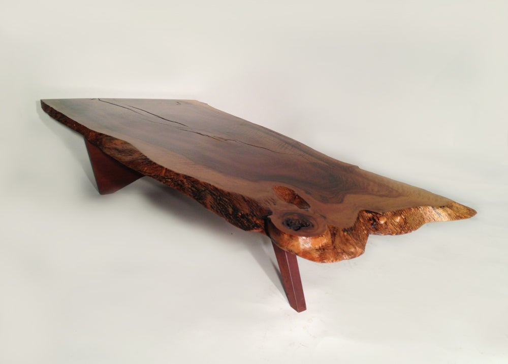 A large and highly figured and thick free edge Walnut slab top having several different types of grain patterns. Burling to edges of top as well. Walnut slab and leg configuration supporting top.