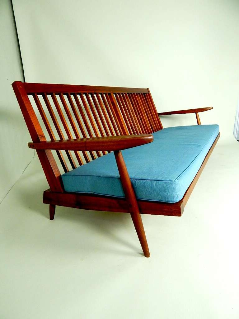 A sofa/bench having a deep cushioned seat angled for comfort and full back cushions. This is a classic  Nakashima form that came in several sizes.