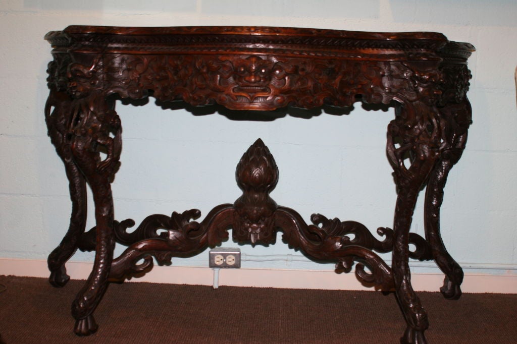 Elegant Chinese Export Rosewood Console Table. Ornately carved dragons, cloud patterns, and archaic motifs. The serpentine carved top, carved with stylized dragons above a conforming open reticulated frieze of dragons raised on carved cabriole legs