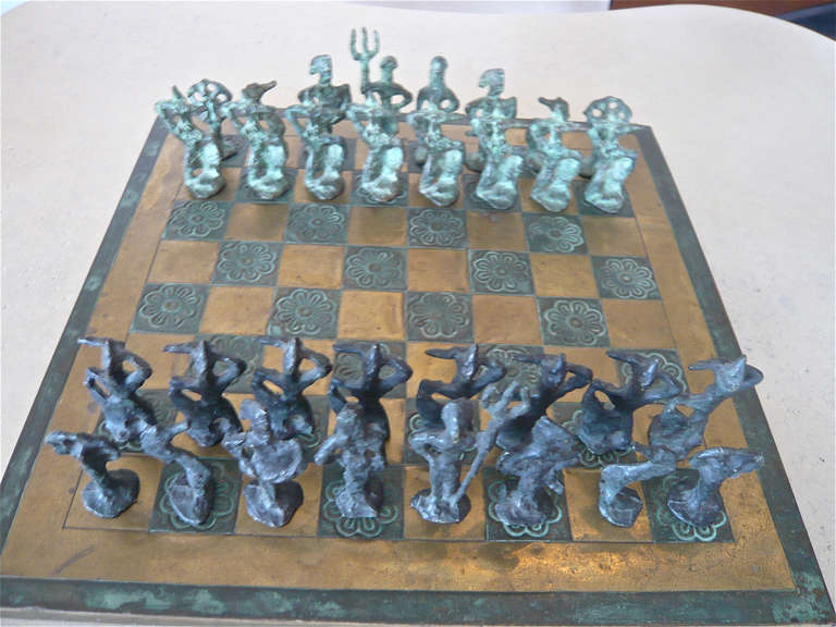 Cast bronze pieces,verdigris application to one set on hammered brass chess board.
The board measures 15.75