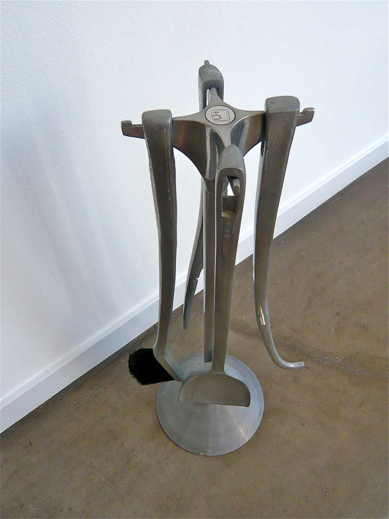 Modernist fireplace tool set consisting of a 2 piece log holder,broom and shovel,hanging neatly from a notched stand.