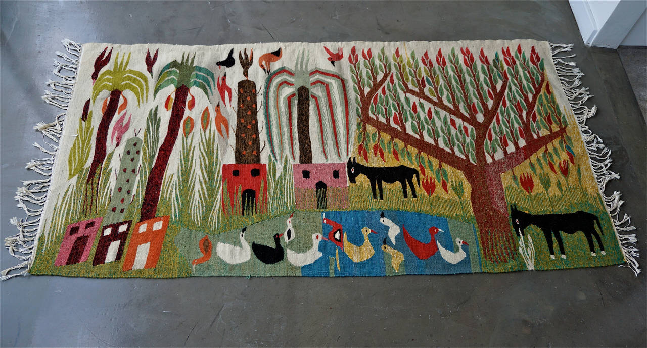 Handwoven and dyed depicting birds in the trees, donkeys grazing and ducks in the water. Unsigned but having a European sensibility. Can be used as a floor rug as well.