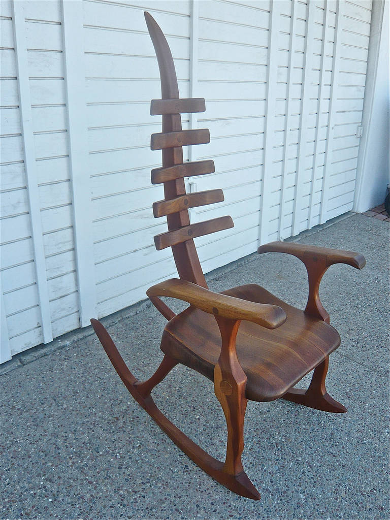 African American woodworker, James Camp was a self-taught craftsman working out of his studio in Philadelphia, Pennsylvania in the 1970s and 1980s.This spine-backed rocker was carved and sculpted out of walnut, etched and signed 