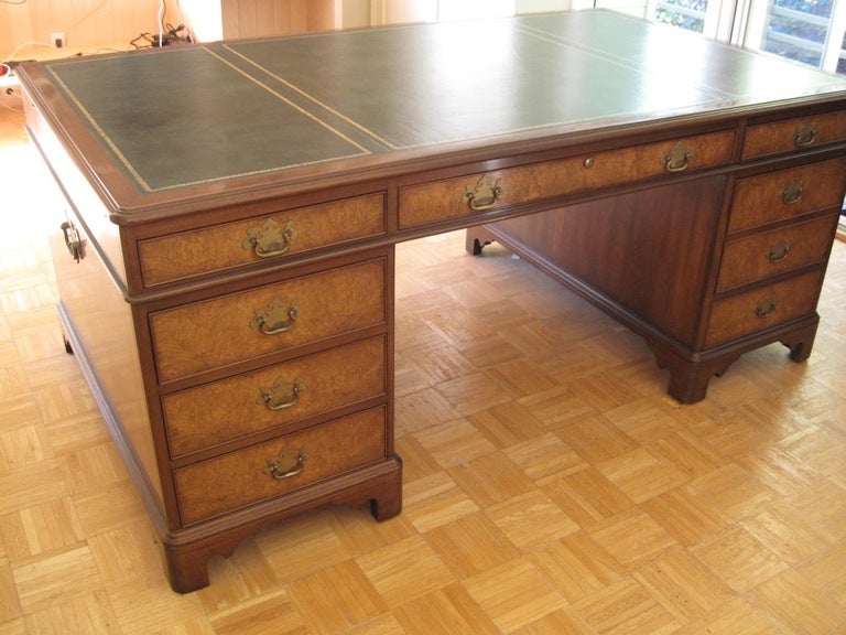 In mint condition, Kittinger Georgian style mahogany and olive burl wood partner's desk, circa 1984.  Together with the desk top having its original forest green leather insert.  Desk drawer and cabinet lock set and keys included, and original. 