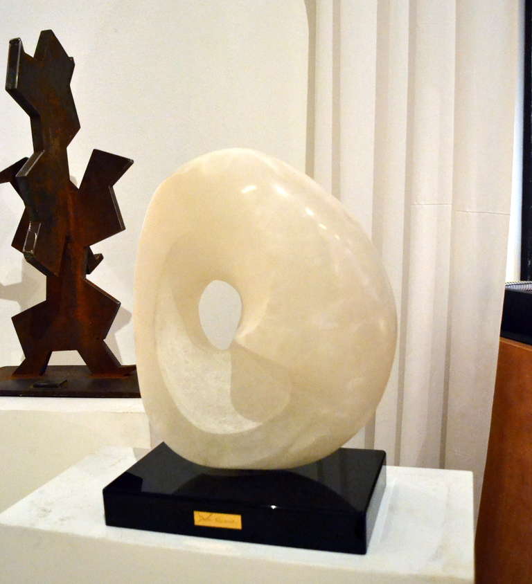 Acquired from the artists private collection is this large abstract in alabaster, hand-carved and polished. It sits upon a black Lucite base that offsets it handsomely. A brass name plate identifies the artists name. This sculpture comes with a