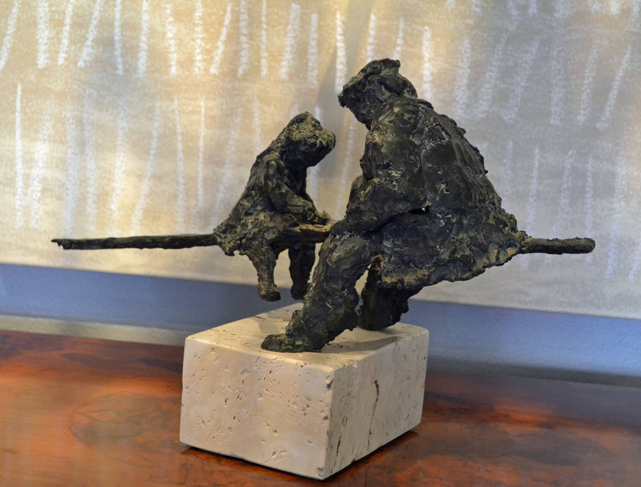 This bronze sculpture, circa 1965, of two figures - one a young girl. The other a older man is full of character, whimsy and moment. Both figures on a seesaw are mounted on a Travertine base. The bronze sculpture extends beyond the base at each end,