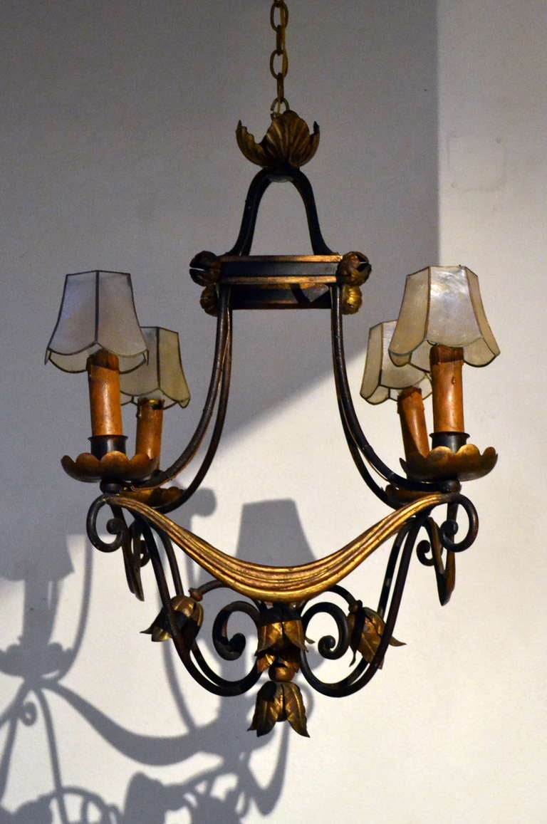 Inspired by the Neo-classical period, when only the French could create this amazing classic iron and gilt metal cage form chandelier so perfectly.  Its metal rosettes, natural sea shell shades and gilded draped swags are topped off by a matching