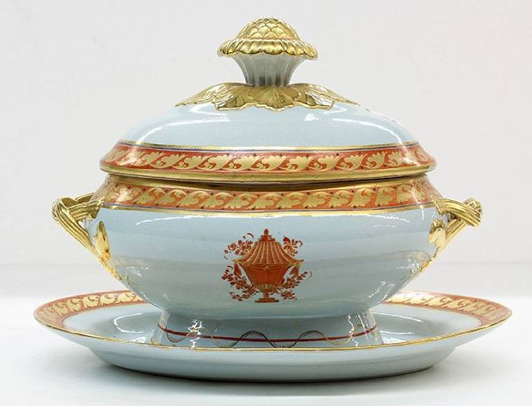 Comprised of partial-gilt and polychrome decorated body executed in the Lowestoft taste. The lidded tureen having a gilt floral knob handle above a gilt and red oxide band at the rim, the body with braided applied handles having American eagle