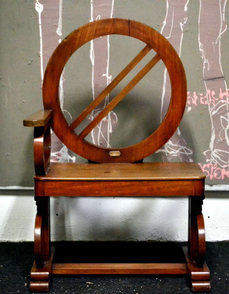 Most likely a captains chair that would have been placed next to the helm on a very fine ship or yacht.  Dated early 19th century and characterizing various periods of both English and even Asian furniture styles all in one single one-armed chair. 