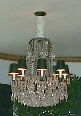 This rare, hard to find chandelier in a highly sought-after, fleur-de-lis design (similar to the popular bird cage style) is delicately festooned with individually attached, single treaded, predominantly pear-shaped crystals. 

This fixture was