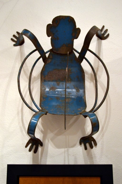 “Monkey See Monkey Do,” except you’ll never see another monkey do what this monkey is doing.  Why it’s a basket on the floor, a sculptural hook when hung on the wall.  It's metal, with a patina of original blue paint peeled away from years of