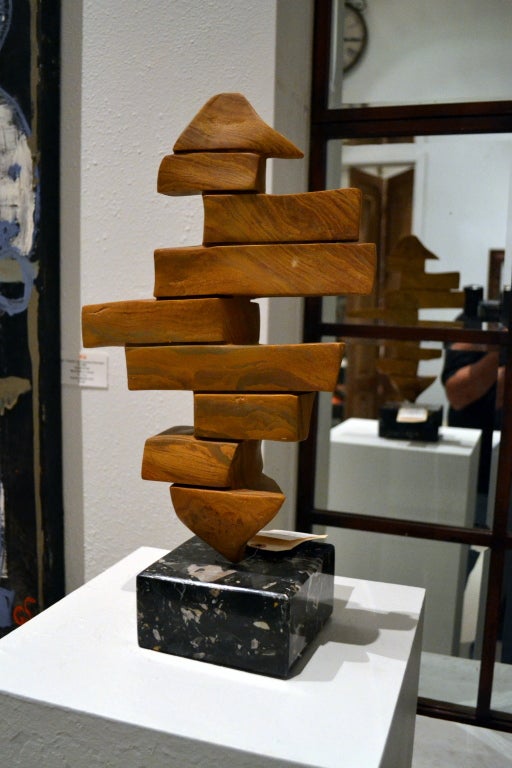 It looks like blocks of wood, stacked in a random manner, one on top of the other.  Instead, the blocks are made of hand-carved soap stone.  However, the blocks of stone are not separated, that is merely the illusion the artist wants you to see. 