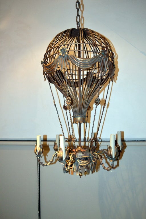 This chandelier is in the form of a Hot Air Balloon, with a bronze-like metal patina overall, plus hints of gold leaf through-out.  Six arms each take a candelabra size bulb, 40 watt max allowed; this fixture looks great with or without lamp shades