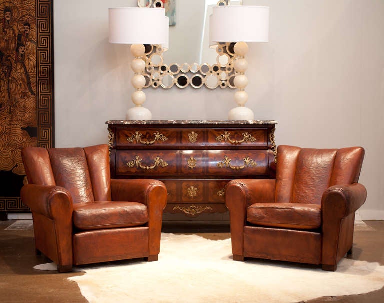 French vintage pair of full leather club chairs, all original, professionally reconditioned, with leather cushions and wooden feet. Very comfortable, we love the scalloped back.