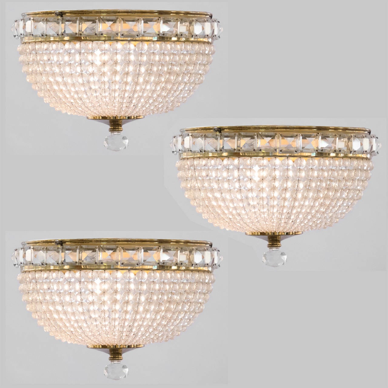 French vintage set of three brass, glass, and crystal ceiling fixtures in the Empire style. Can be purchased individually. Each holds one medium base bulb, rewired for the US.