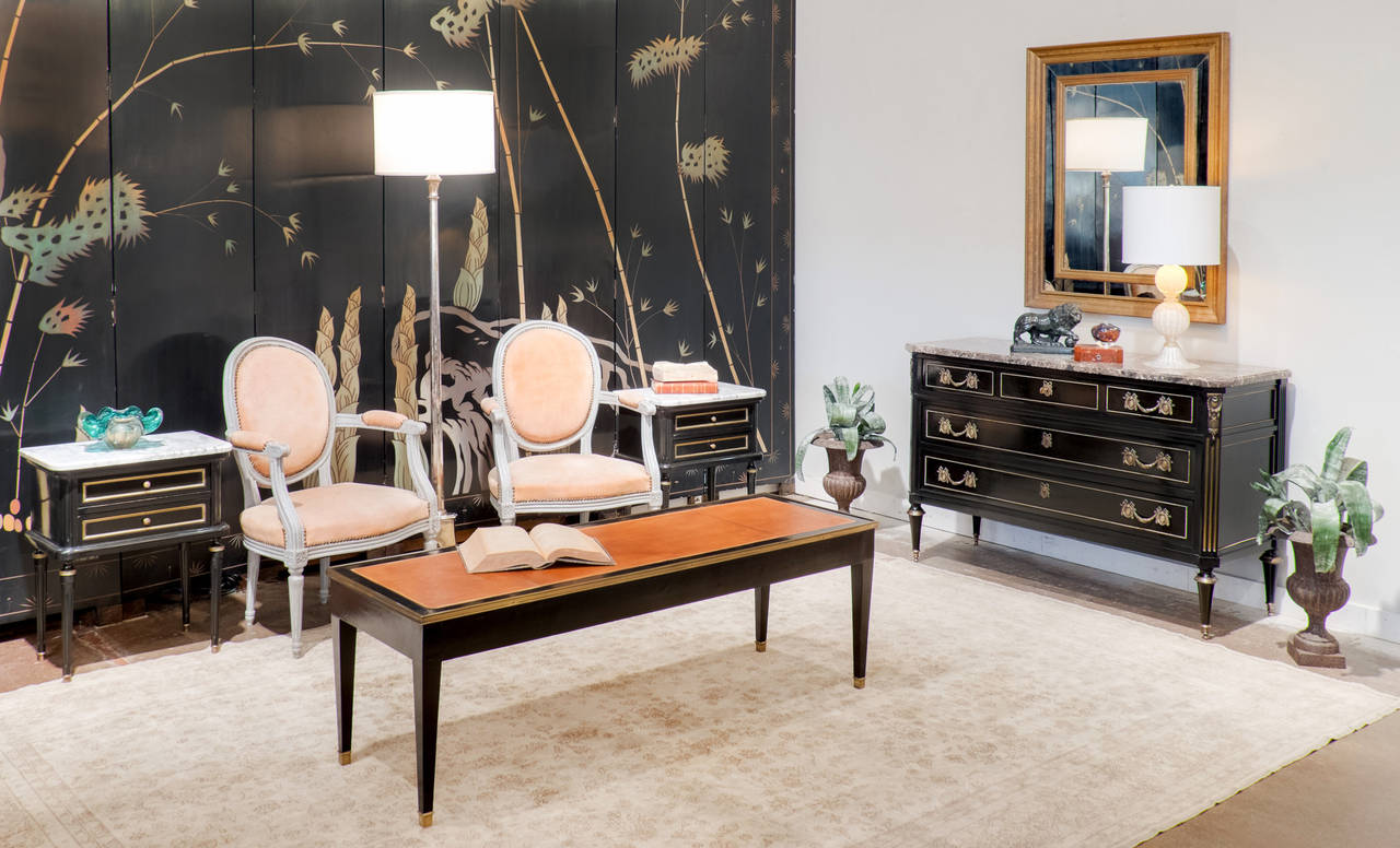 French Louis XVI pair of end tables in the style of Maison Jansen, ebonized mahogany, finished with a lustrous French polish, and Carrara marble tops. Hand-carved fluting, brass trim on each dovetailed drawer and the tops of the legs, and brass