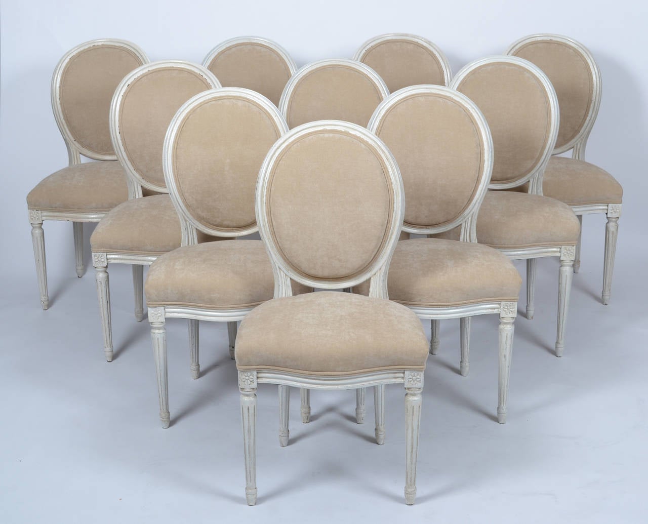 Antique French Louis XVI style set of ten, medallion back, dining room chairs. Hand-carved and patinated beechwood frames, professionally reupholstered in a beige chenille velvet. Four of the chairs have an extra vertical support on the back of the