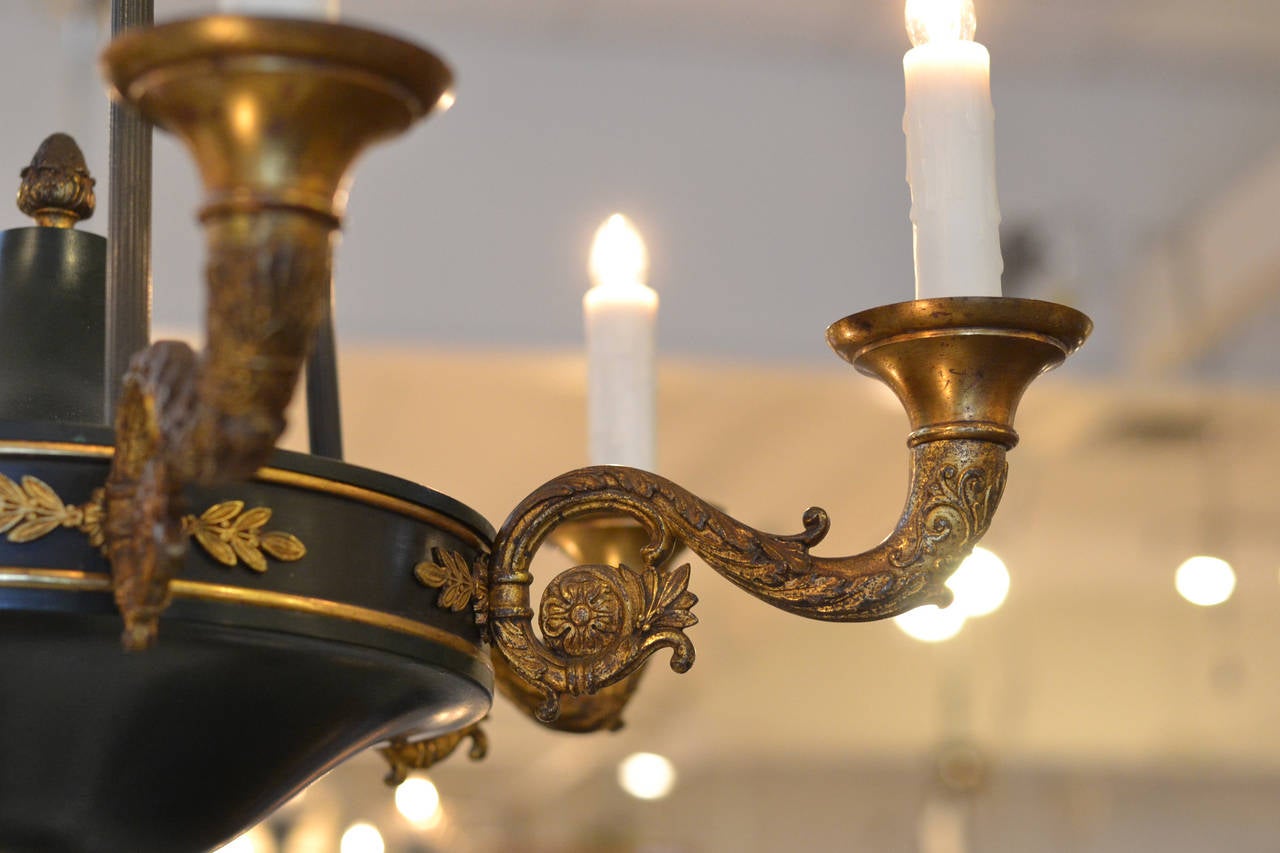French Empire style gilded bronze and green painted tole chandelier with six branches, cast floral details and acorn finial and matching canopy. Six candelabra lights, rewired to US standards. We couldn't resist the finely cast work on the bronze.
