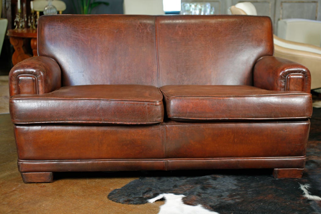 French Vintage lambskin leather love seat. Comfortable, stylish, and in very nice condition. Unusual leather upholstered feet.