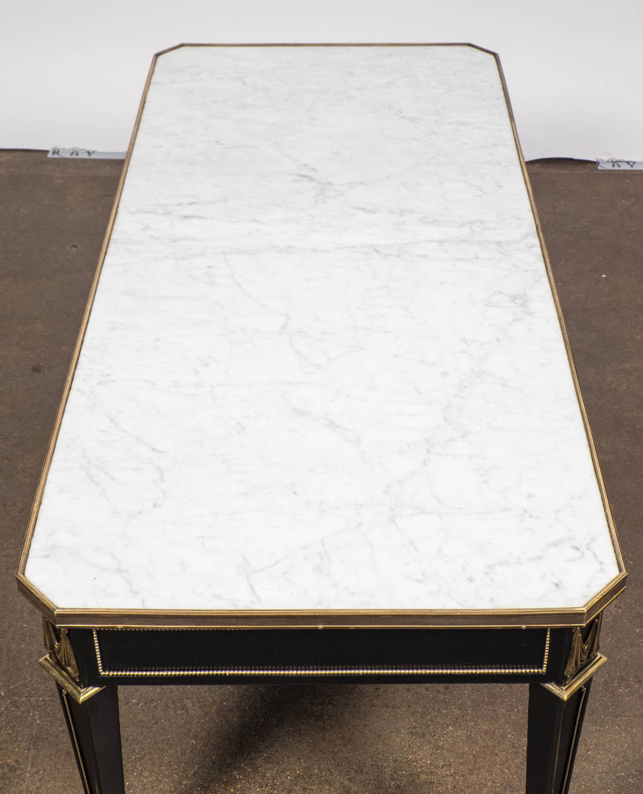 Vintage French Directoire style coffee table in ebonized mahogany with a lustrous French polish, Carrara marble top, and gilt bronze trims.