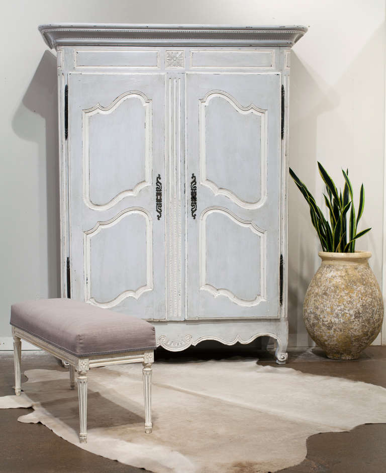 Antique French Louis XV armoire in solid, hand painted oak and forged iron hardware. We love the hand carved details, from the decorative frieze to the  beautifully molded paneled doors, all the way down to the scrolled feet. This piece also boasts