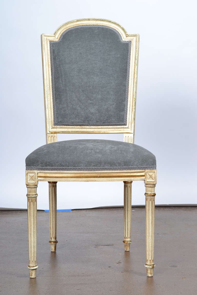 Rare wonderful antique set of six Louis XVI style dining chairs in  hand carved, lacquered beechwood with fluted legs and gold leaf accents. Professionally reupholstered in a blue-grey velvet blend. Flawless  style, comfortable large seating. Very