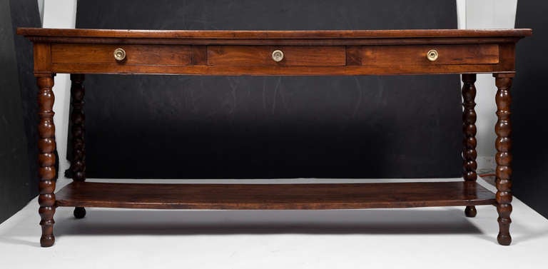 From Lyon in the Rhone valley, French Louis Philippe period solid walnut silk traders console table with three dovetailed drawers, hand turned legs, and bottom shelf. Perfect  proportions and very strong construction. Lost wax cast bronze hardware.